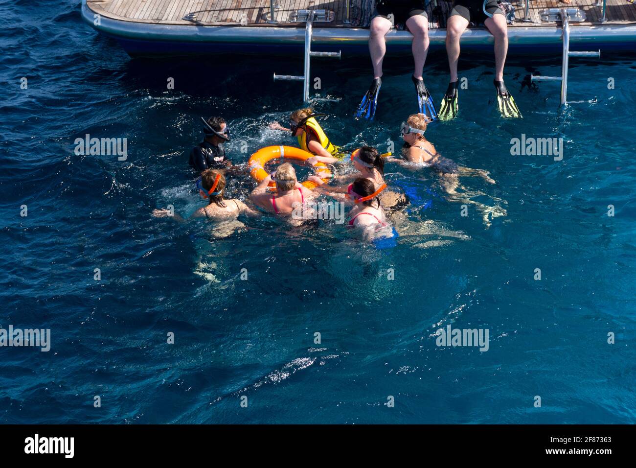 Groupe de personnes à la natation costumes plongée en apnée à la mer bleue avec instructeur Banque D'Images