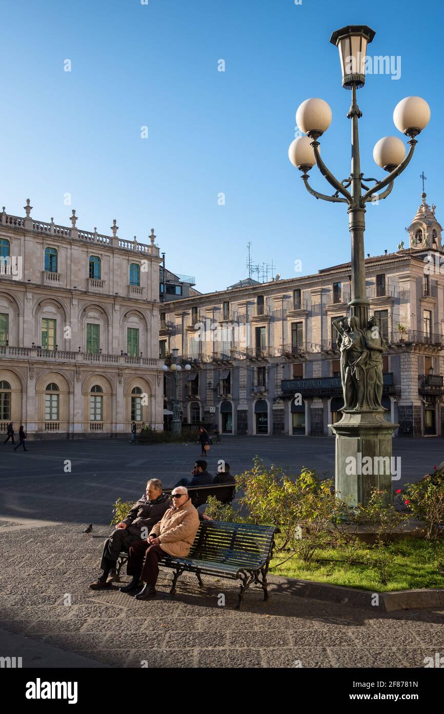 Des hommes âgés non identifiés qui profitent du soleil sur la place du Duomo à Catane, en Sicile, en italie Banque D'Images