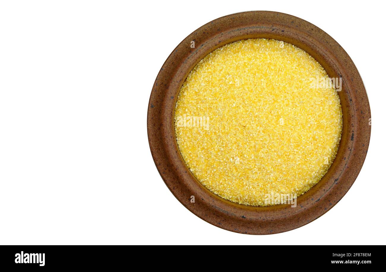 Polenta ou farine de maïs dans un bol, vue de dessus, isolée sur blanc. Tas de semoule de maïs