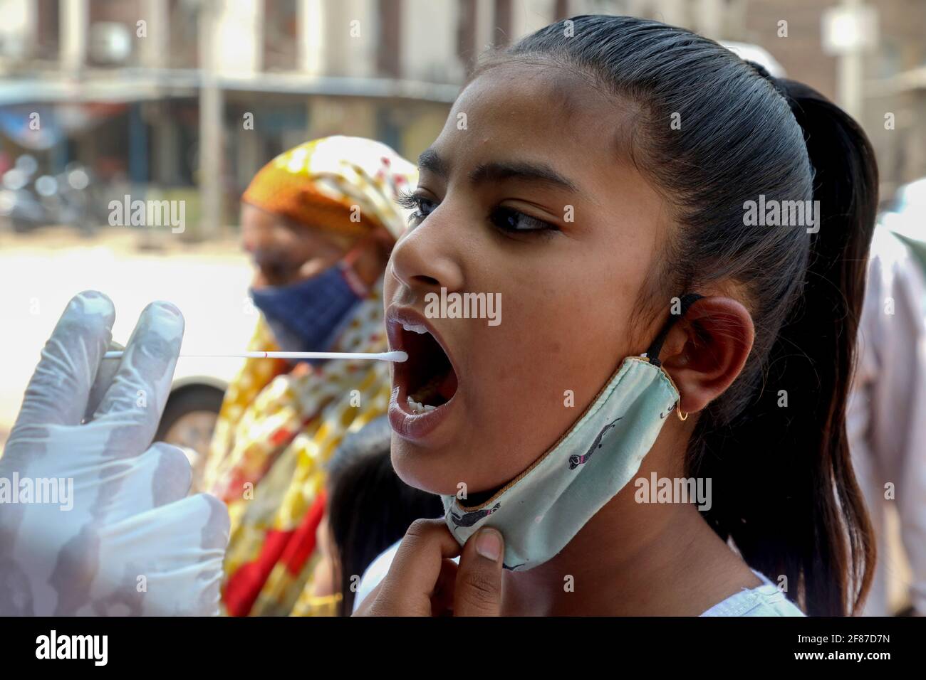 New Delhi, Inde. 12 avril 2021. Un professionnel de la santé portant un équipement de protection individuelle (EPI) recueille un échantillon d'écouvillon buccal auprès d'un enfant pour un test de réaction en chaîne de la polymérase (RT-PCR) de transcription inverse Covid-19 au centre d'essai routier de la zone industrielle de Wazzirpur à New Delhi. L'Inde a enregistré 168,912 nouveaux cas de Covid-19, soit la plus forte augmentation d'un jour et 904 décès au cours des 24 dernières heures. (Photo par Naveen Sharma/SOPA Images/Sipa USA) crédit: SIPA USA/Alay Live News Banque D'Images