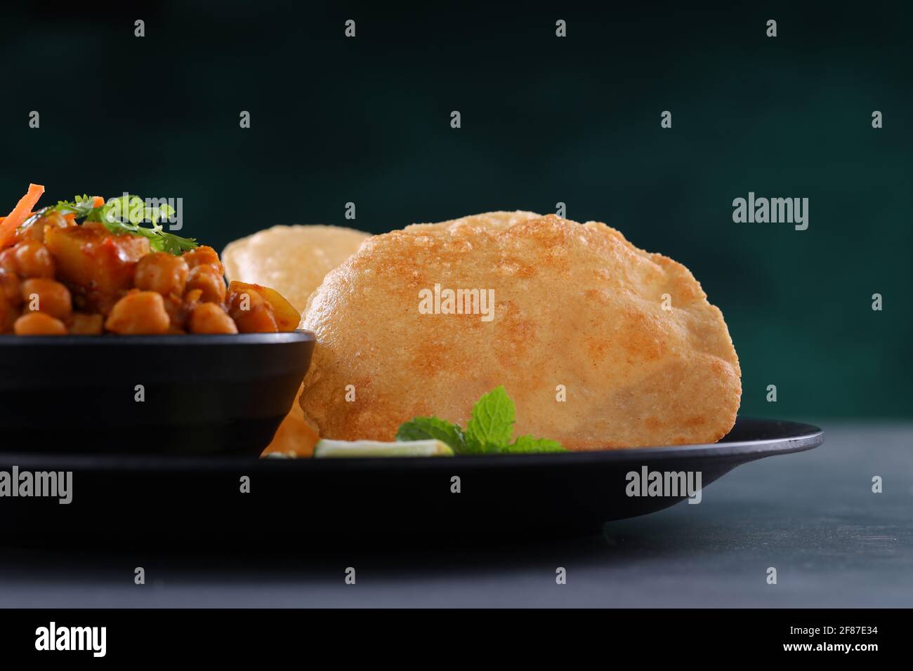 Petit-déjeuner indien  Poori avec cari de masala de pois chiches, savoureux plat indien fait à l'aide de farine de blé à usage général qui est disposé dans une plaque noire avec Banque D'Images