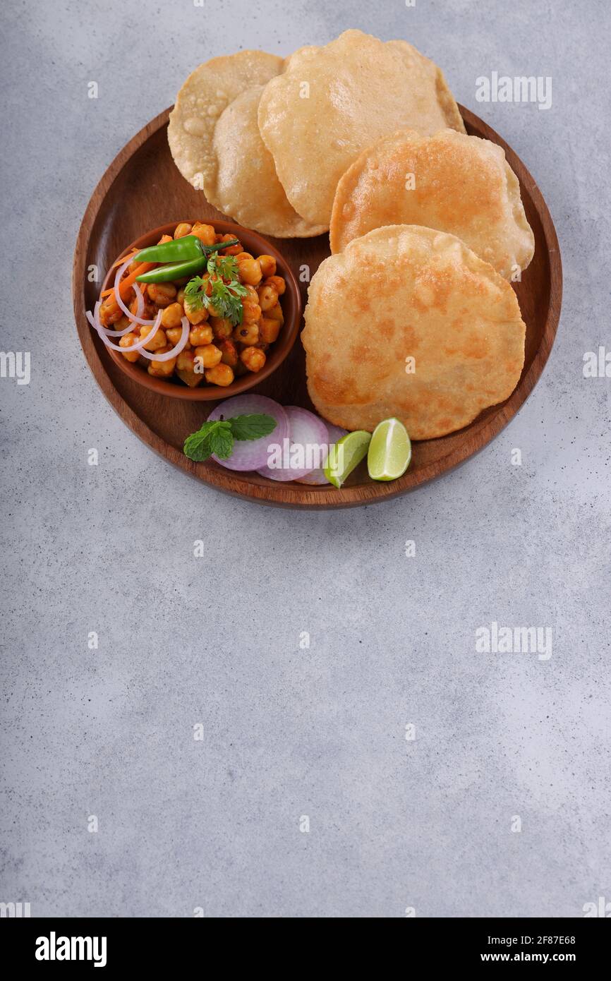 Petit-déjeuner indien  Poori avec cari de masala de pois chiches, savoureux plat indien fait à l'aide de farine de blé à usage général qui est disposé dans une plaque en bois avec Banque D'Images