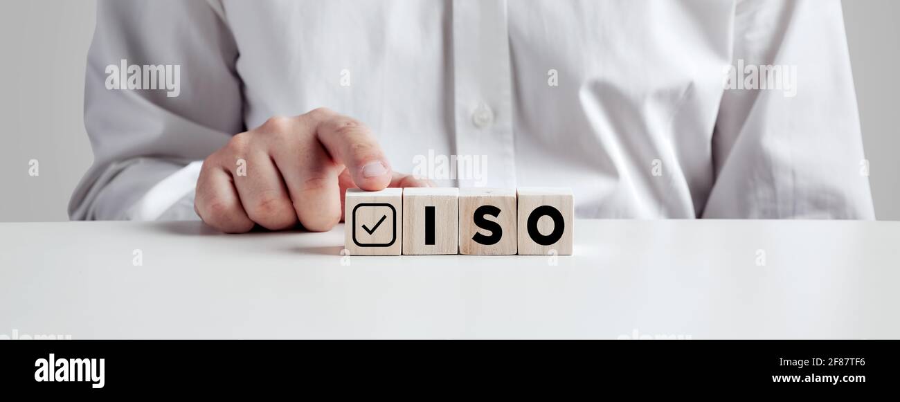 Homme d'affaires appuyant son doigt sur les cubes en bois avec l'abréviation ISO avec une coche. Concept de certification de contrôle qualité ISO. Banque D'Images
