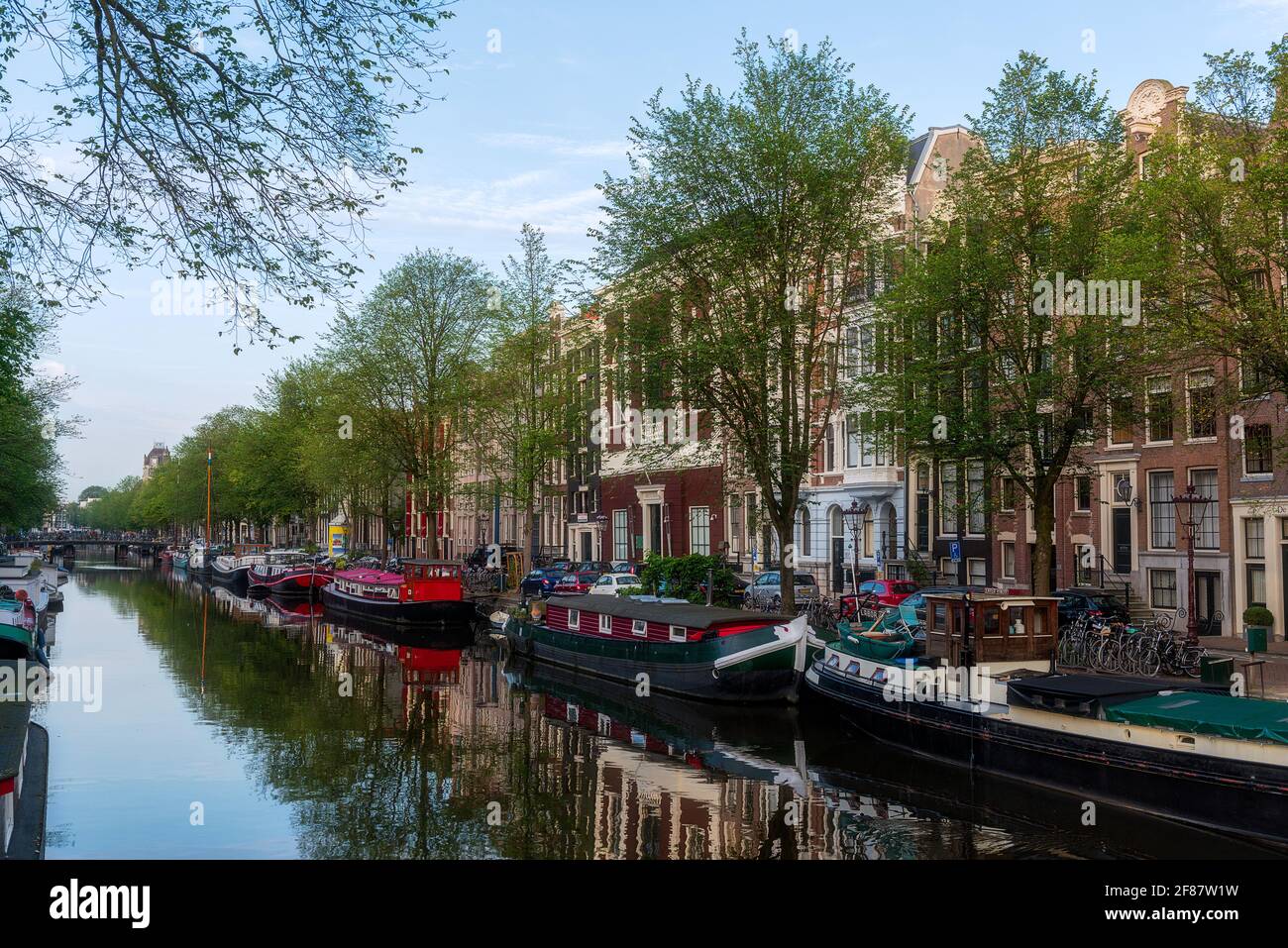 Amsterdam City Life - Bateaux sur le canal et personnes voyageant en vélo. Banque D'Images
