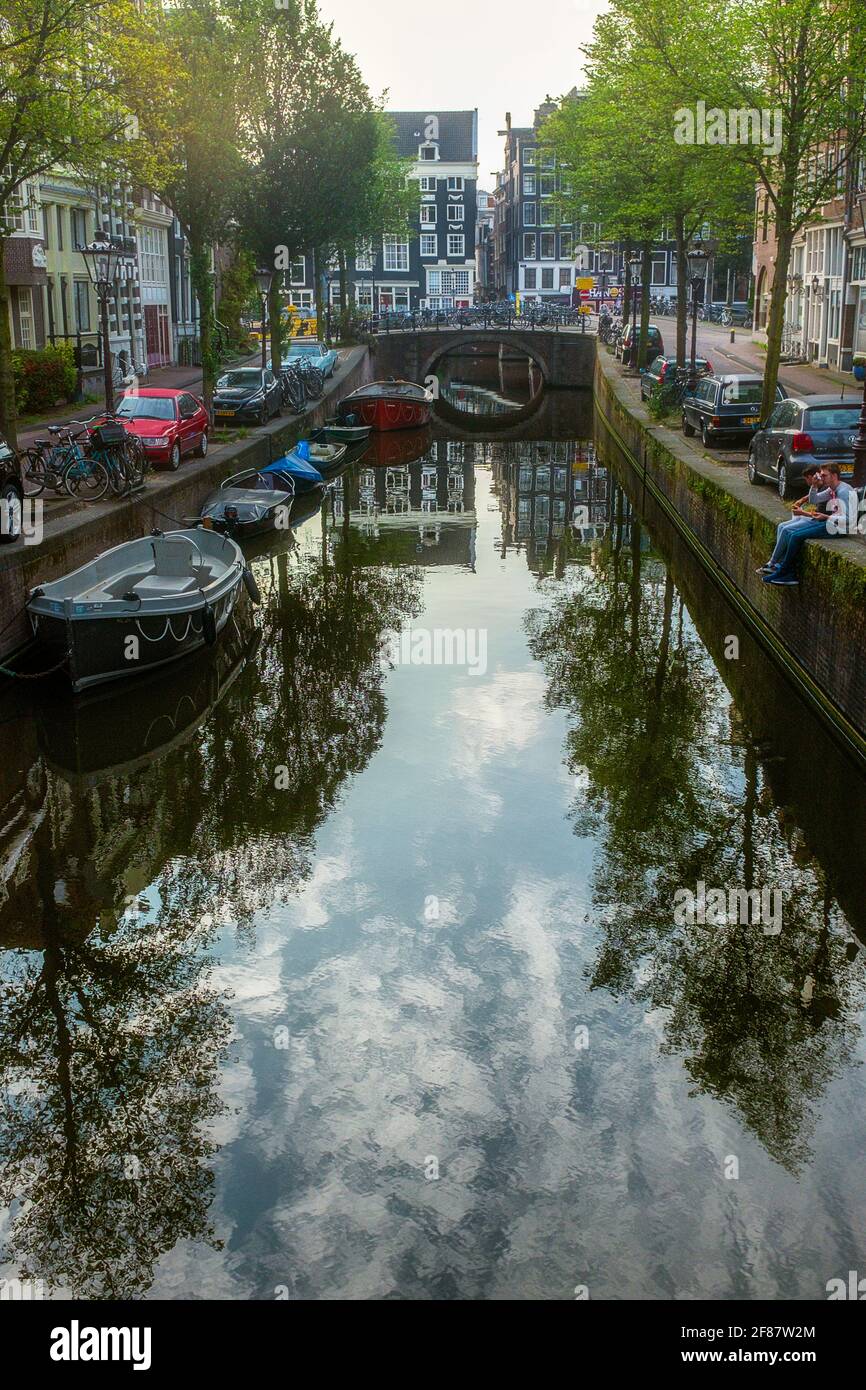 Amsterdam City Life - Bateaux sur le canal et personnes voyageant en vélo. Banque D'Images