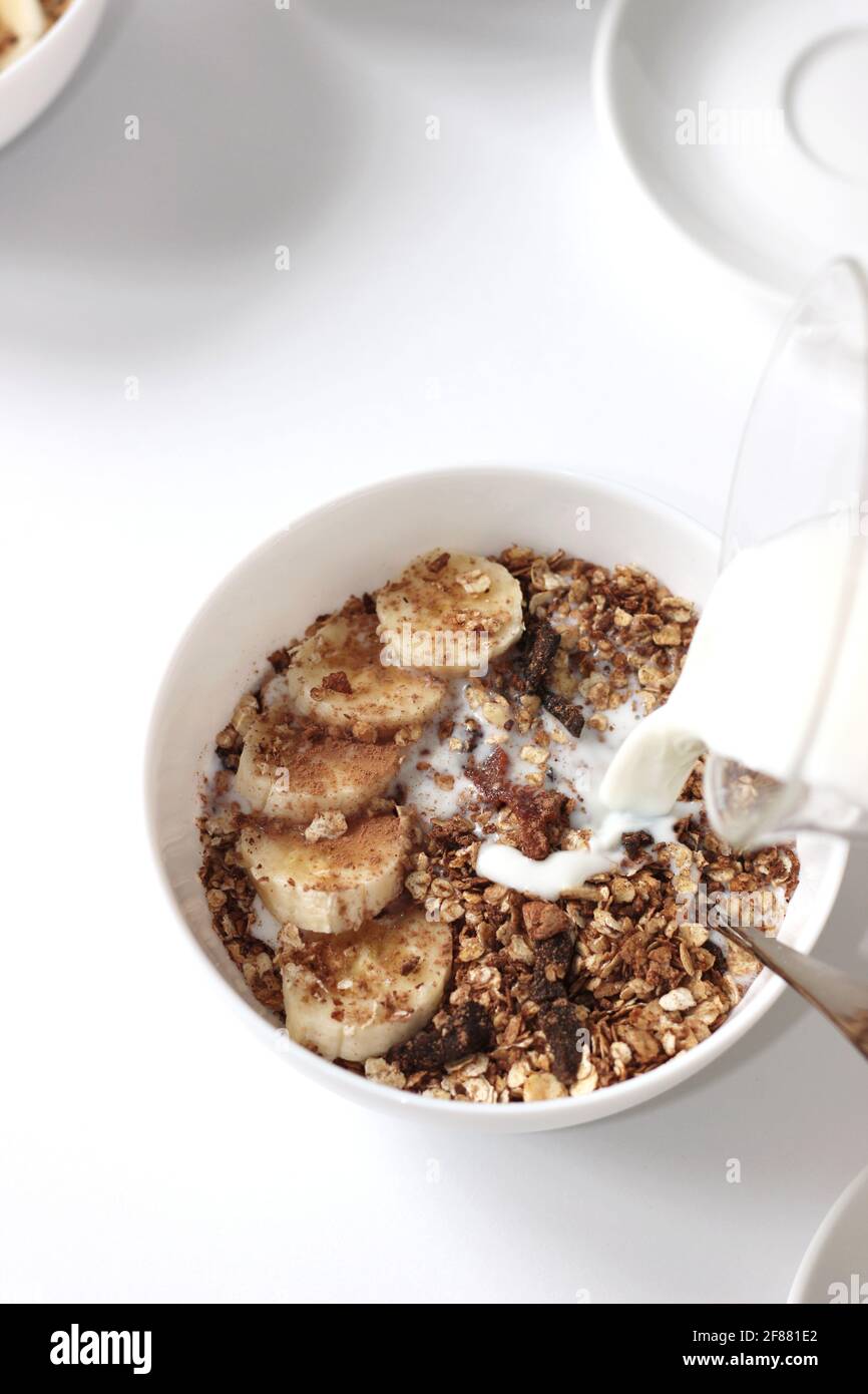 Verser le lait dans le bol à céréales avec des tranches de banane. Préparer le petit déjeuner. Banque D'Images Verser le lait dans le bol à céréales avec des tranches de banane. Préparer le petit déjeuner. Banque D'Images