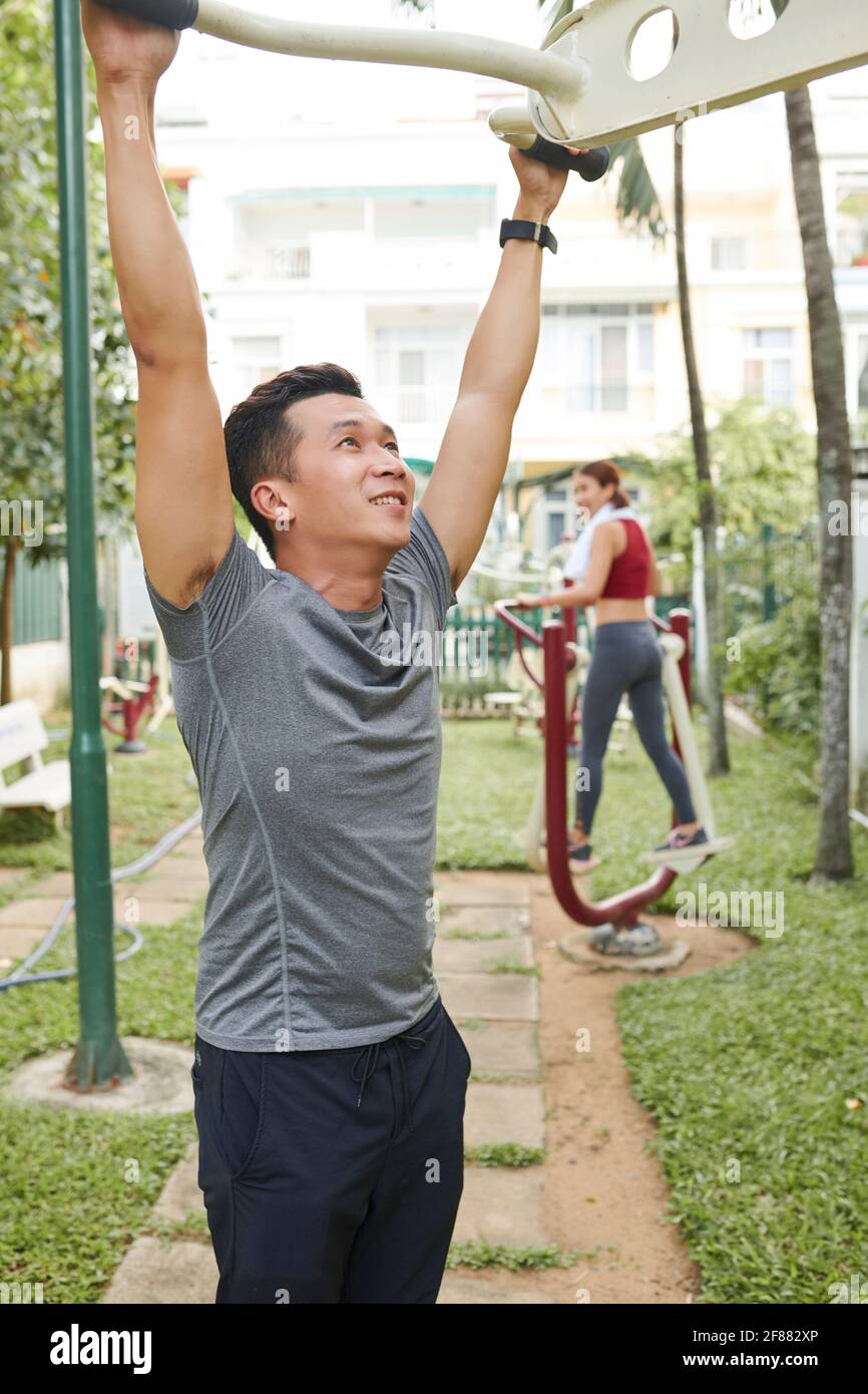 Belle forme jeune homme asiatique faisant des exercices sur l'équipement de fitness dans le parc de la ville Banque D'Images