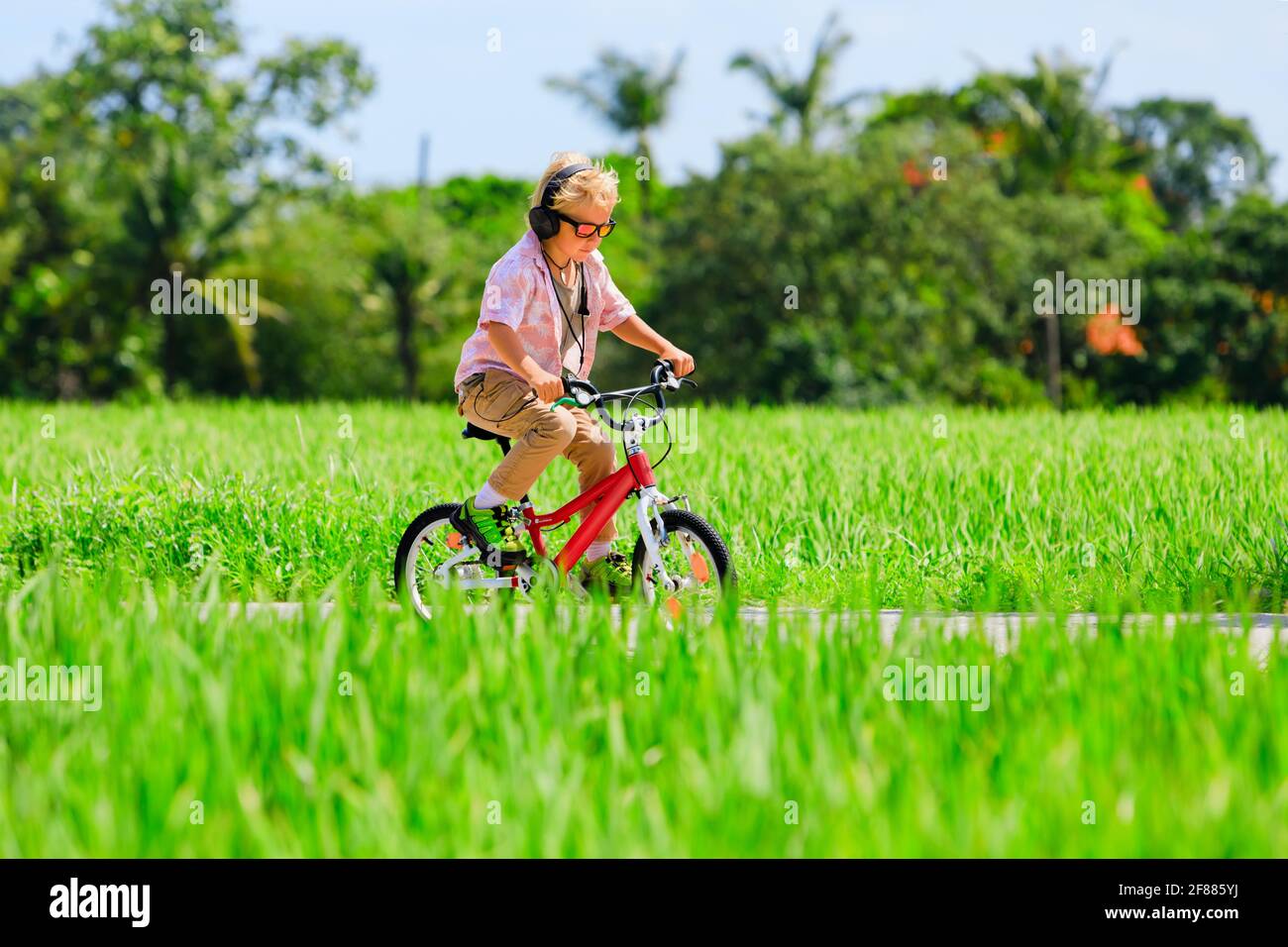 Randonnée à vélo. Jeune enfant pilote dans un casque et des lunettes de soleil à vélo. Un enfant heureux s'amuse sur le sentier. Mode de vie familial actif, sport Banque D'Images