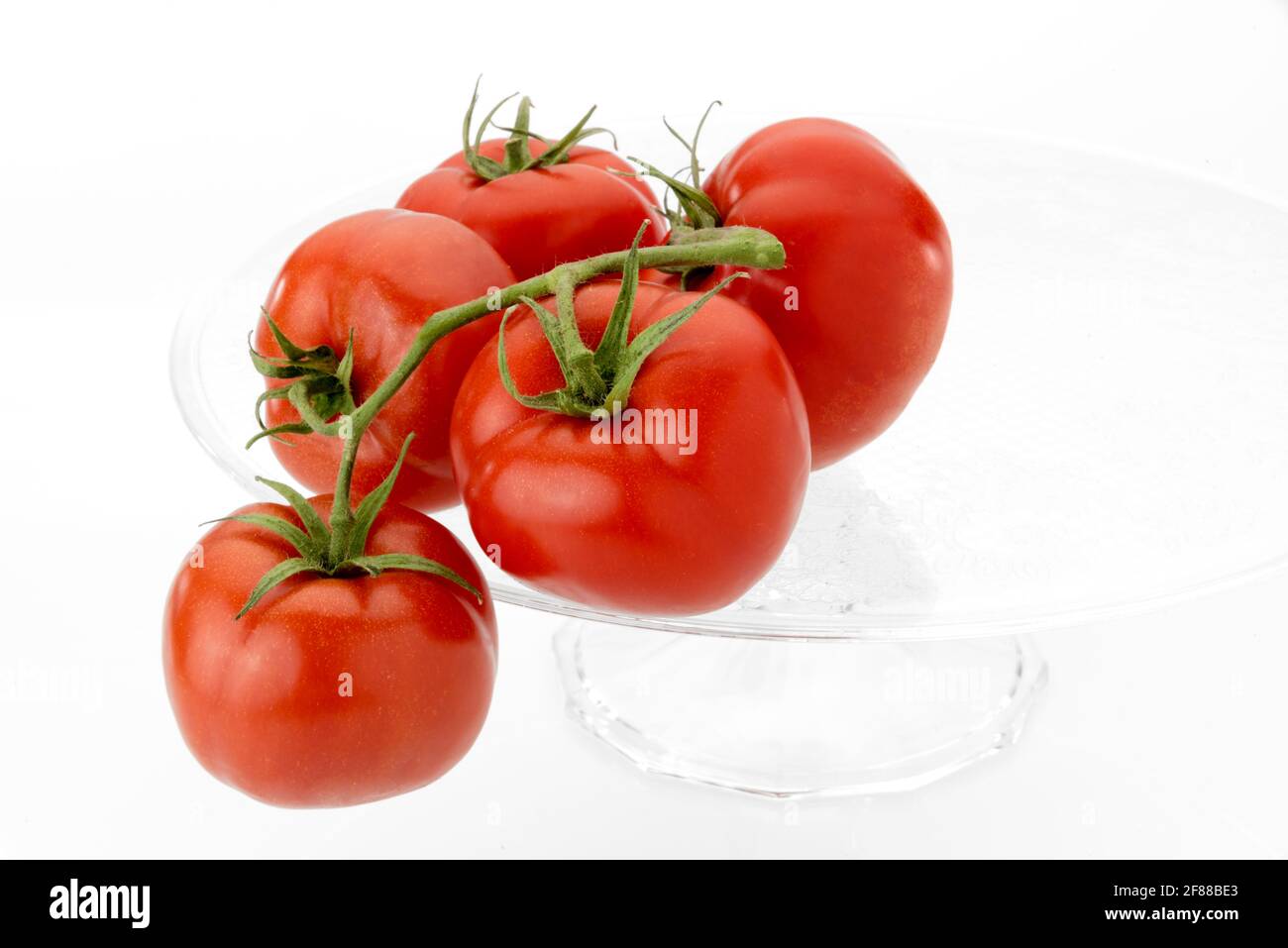 tomates isolées sur une plaque surélevée en verre transparent isolée sur fond blanc. espace de copie Banque D'Images