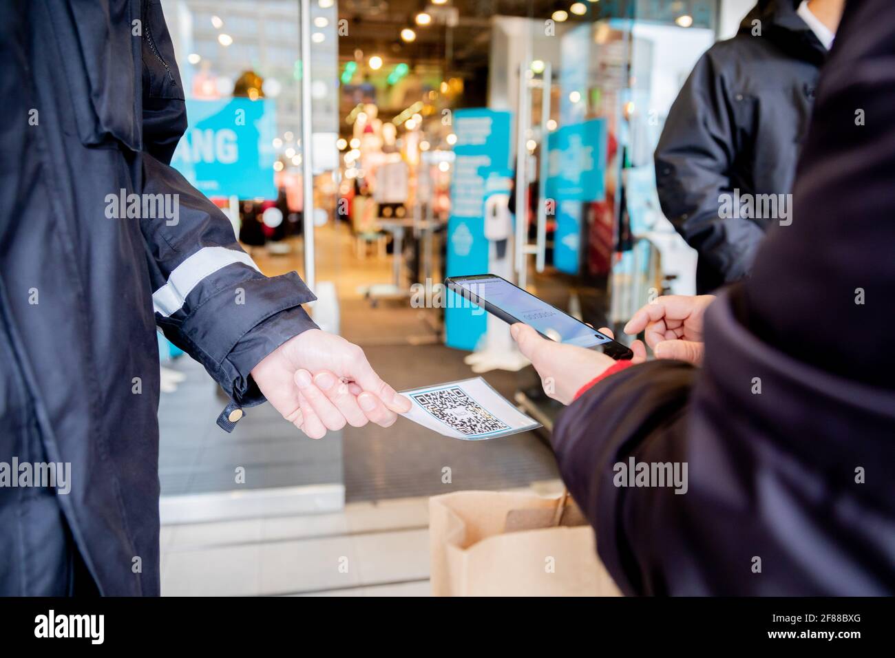 Berlin, Allemagne. 12 avril 2021. Une personne scanne un code QR à l'entrée d'un magasin de vêtements à Alexanderplatz, devant un agent de sécurité, à l'aide de l'application Luca. L'application est utilisée pour fournir des données permettant d'effectuer un suivi des contacts. Credit: Christoph Soeder/dpa/Alay Live News Banque D'Images