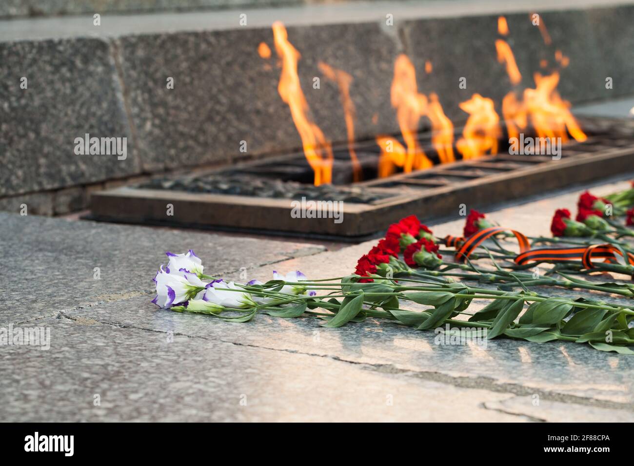 Les fleurs se trouvent près d'une flamme éternelle. Mémorial de la Seconde Guerre mondiale des soldats soviétiques en Russie Banque D'Images