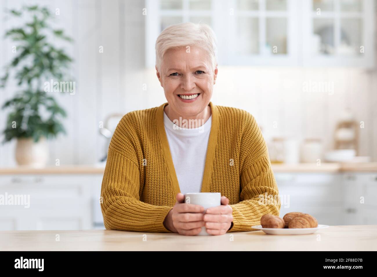 Bonne vieille dame qui boit du café avec croissant Banque D'Images