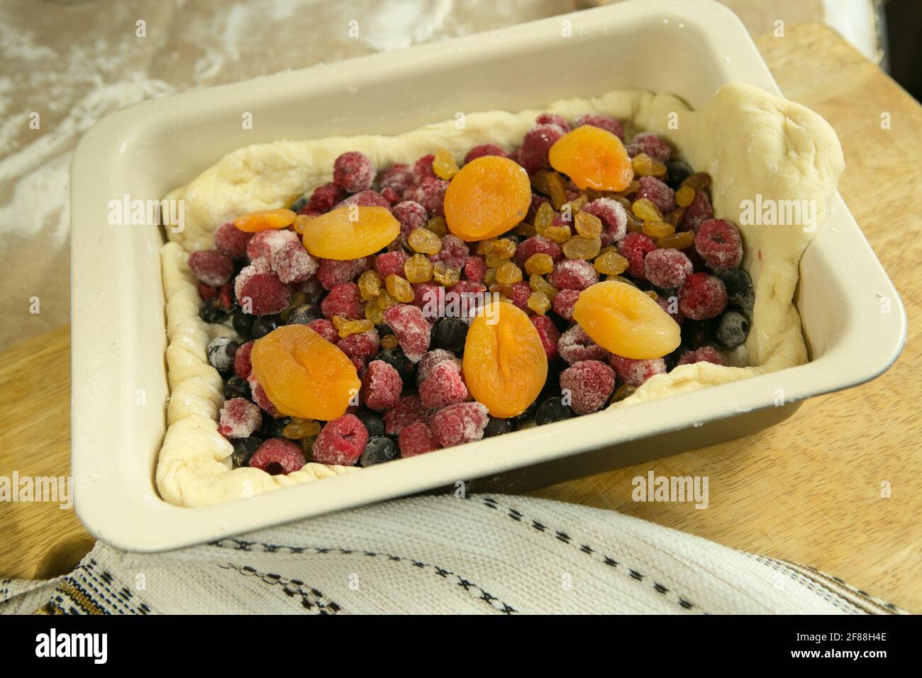 Chaussons de maman. La pâte et la garniture de fruits sont dans un plat de cuisson. Cuisson en quarantaine. Banque D'Images