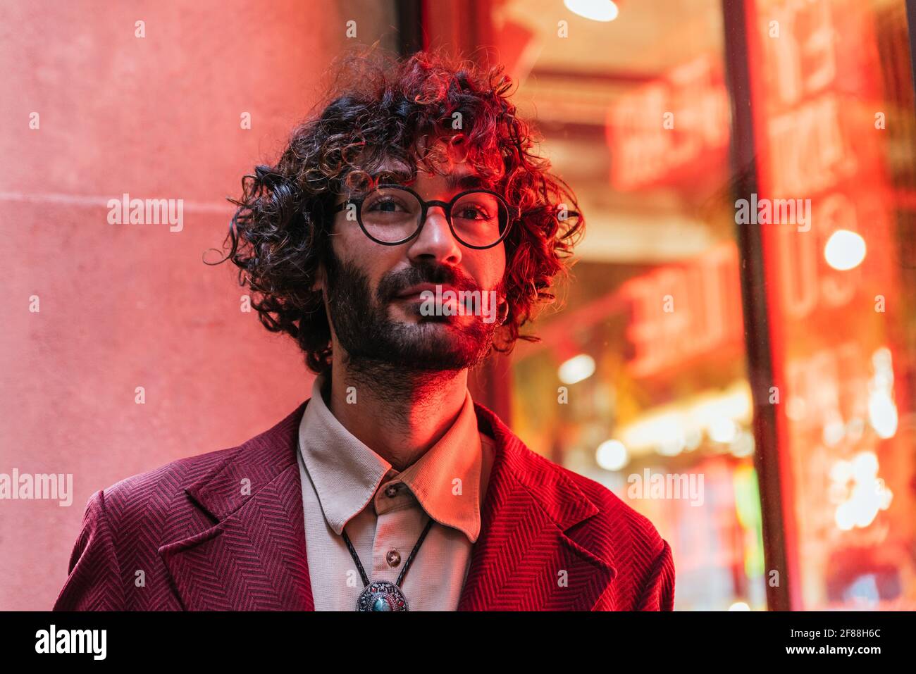 portrait horizontal d'un jeune homme caucasien recevant la lumière néon d'une barre sur son visage. Il s'habille de vêtements et de lunettes tendance Banque D'Images