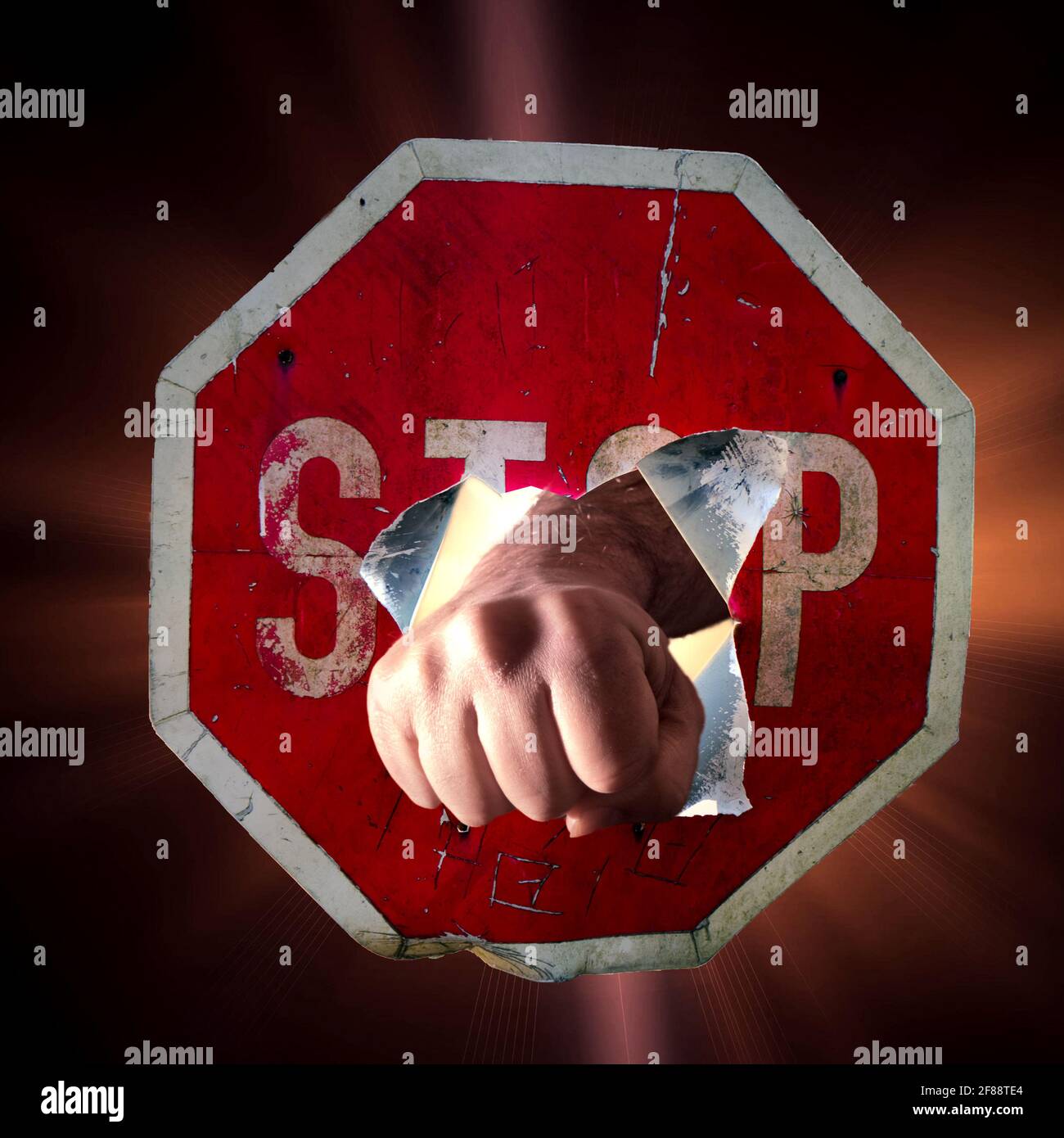 Poing de l'homme pointant à travers le panneau rouge de circulation avec l'inscription Stop, concept pour surmonter, force, affirmation Banque D'Images