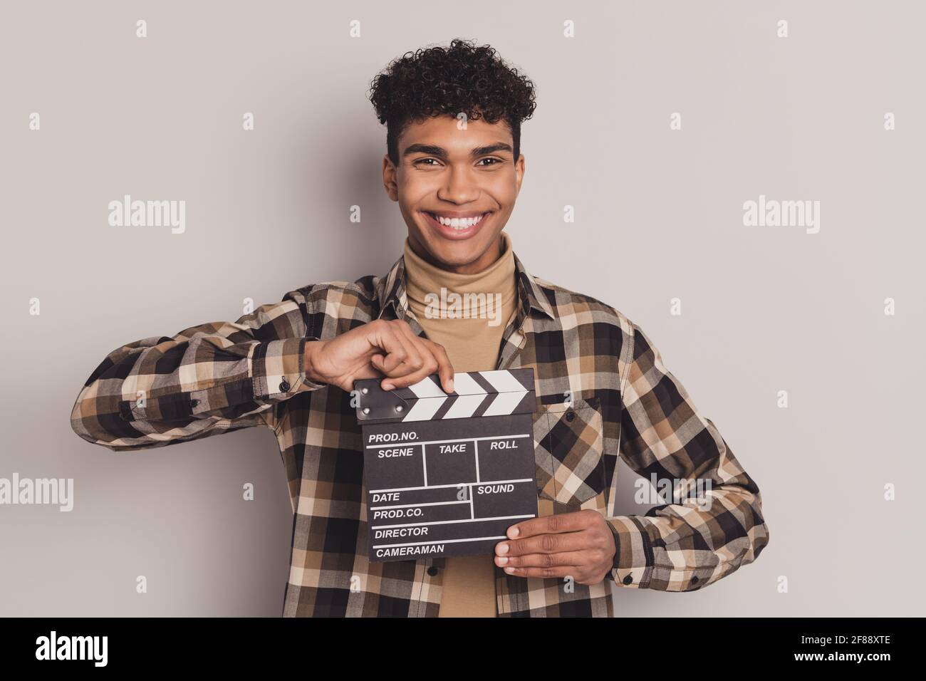 Photo portrait d'un homme qui garde le plateau de casting souriant faisant du film film en chemise à carreaux isolée sur fond gris Banque D'Images