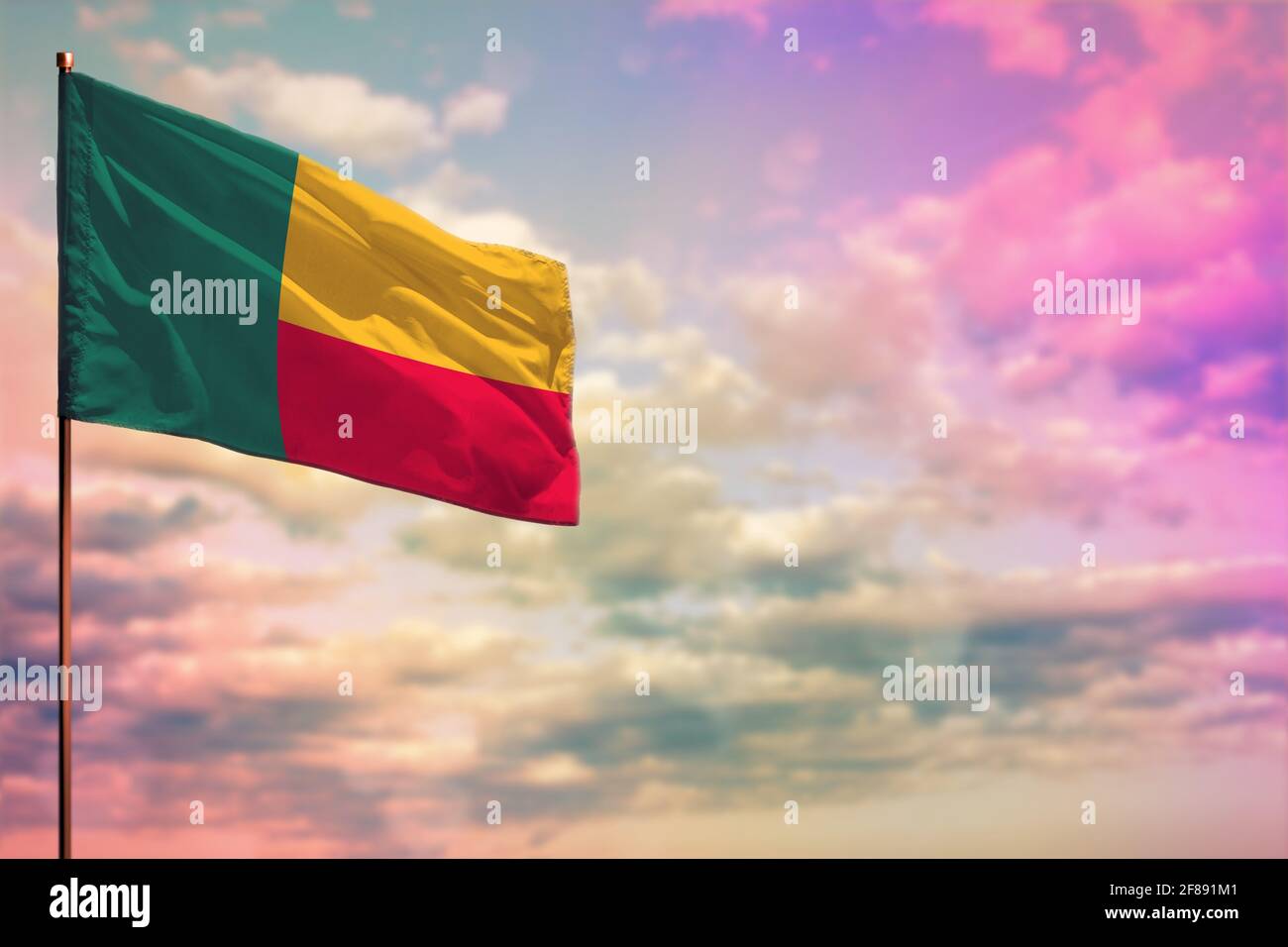 Drapeau du Bénin flambé avec l'endroit pour votre texte sur fond ciel nuageux et coloré. Banque D'Images Drapeau du Bénin flambé avec l'endroit pour votre texte sur fond ciel nuageux et coloré. Banque D'Images