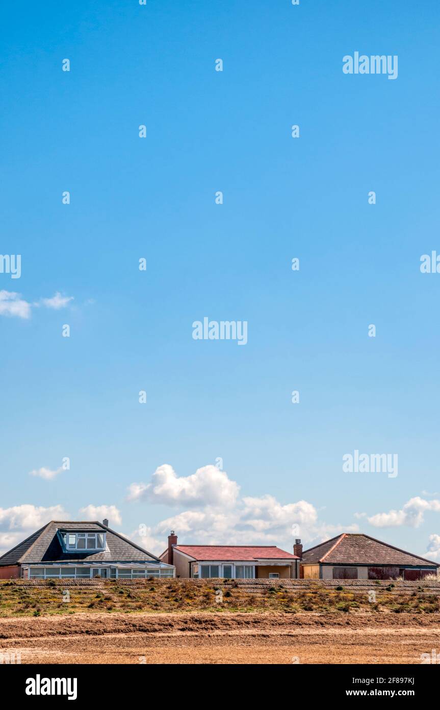 Chalets derrière le mur de la mer à la plage de Snettisham sur le Wash à Norfolk. Banque D'Images