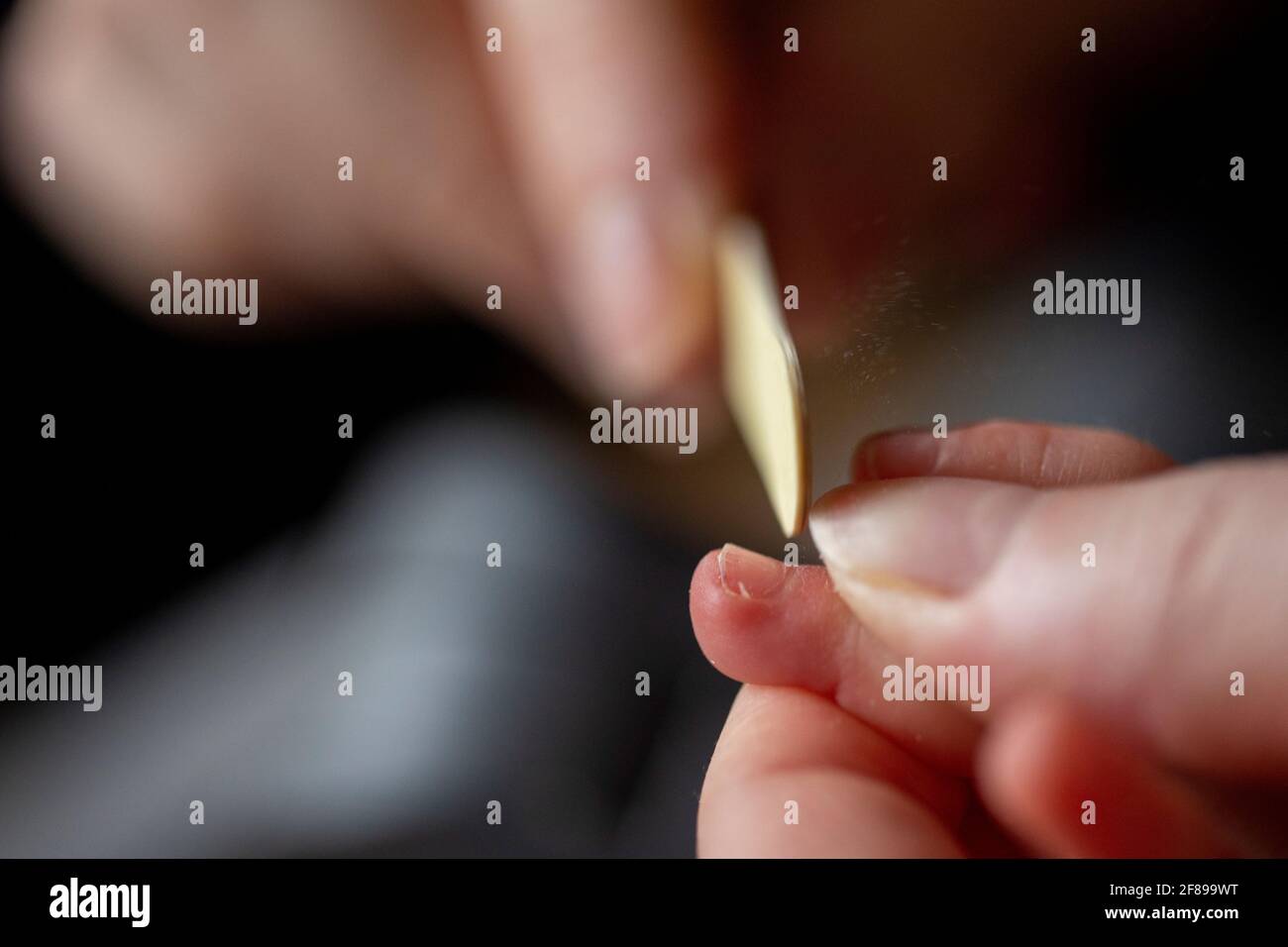 Un portrait rapproché d'une mère qui dépose les ongles d'une petite main de bébé après les avoir clippés. Les ongles des enfants sont classés avec un petit fichier être Banque D'Images