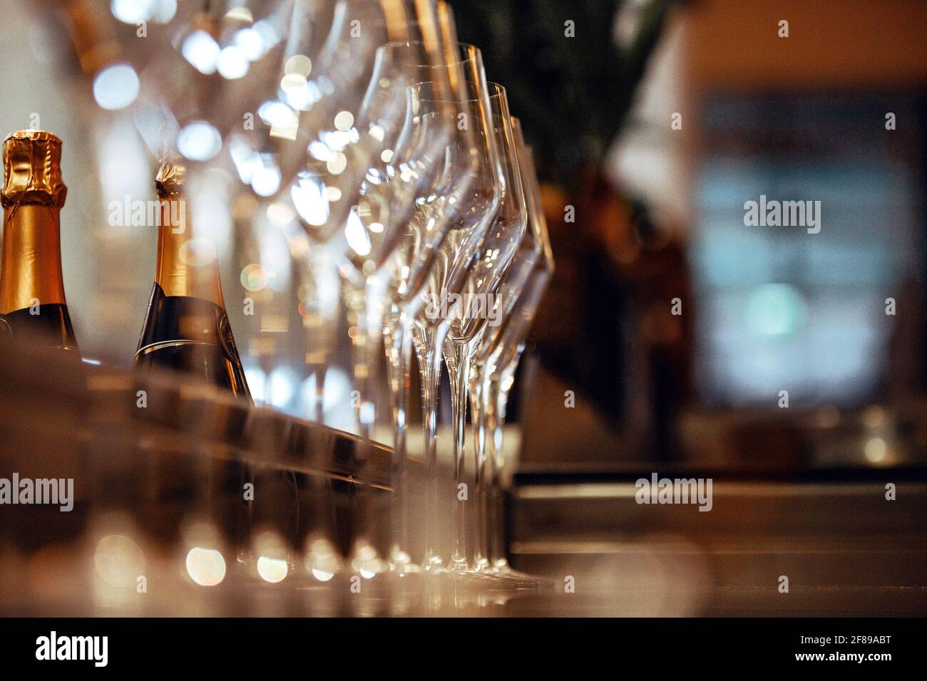 Vider les verres à vin dans une rangée sur le bar, et dans le fond des bouteilles de champagne Banque D'Images