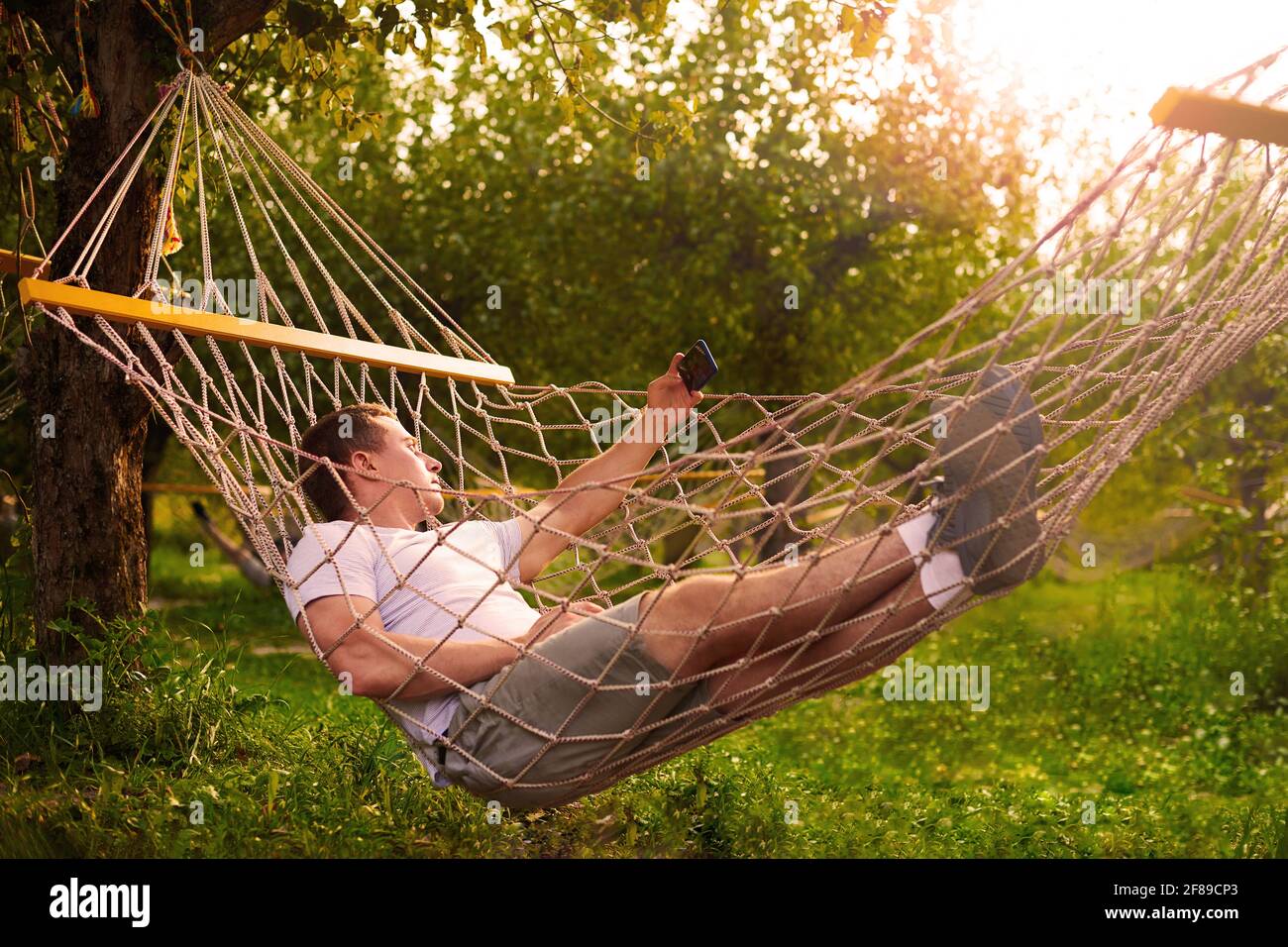 l'homme prend le selfie dans le hamac dans la forêt en journée ensoleillée. concept de repos dans la forêt tropicale Banque D'Images