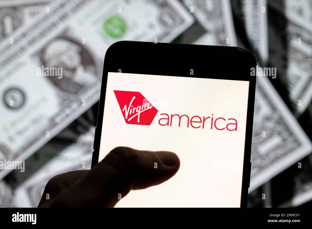 Dans cette illustration de photo, le logo de la compagnie aérienne américaine Virgin America est visible sur un écran d'appareil mobile Android avec la devise de l'icône dollar des États-Unis, symbole d'icône $ en arrière-plan. Banque D'Images