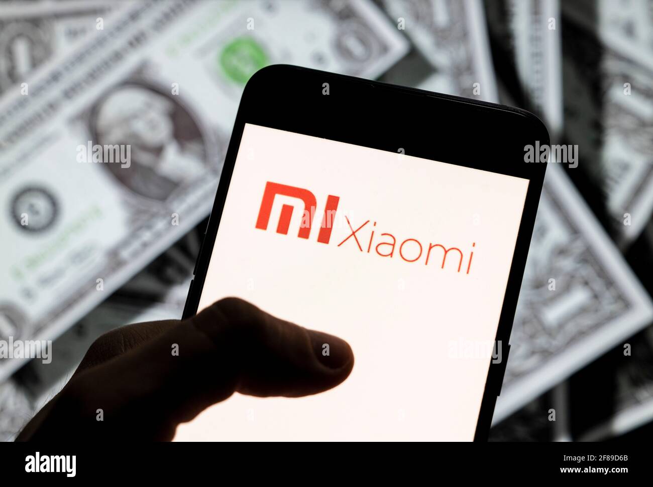 Dans cette illustration de photo, le logo de la société chinoise d'électronique Xiaomi vu sur un écran d'appareil mobile Android avec la devise de l'icône dollar des États-Unis, symbole d'icône $ en arrière-plan. Banque D'Images