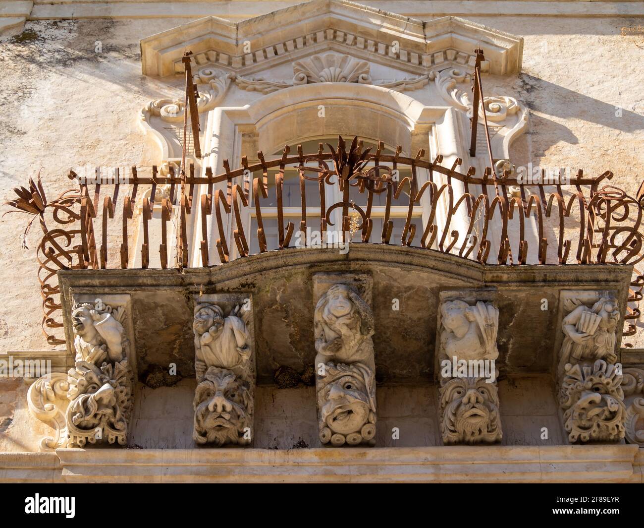 Vue sur les faces sculptées en pierre qui soutiennent un balcon du Palazzo Cosentini baroque, Ragusa Banque D'Images