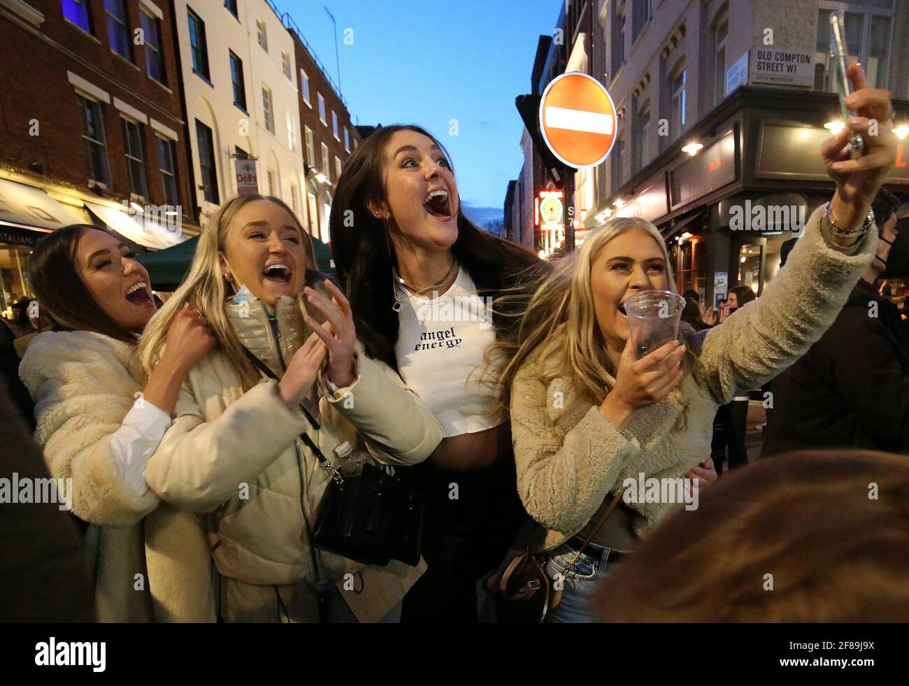 Les gens se réjouissent d'être sortis pour la soirée dans Old Compton Street, Soho, dans le centre de Londres, où les rues ont été fermées à la circulation pour créer des espaces extérieurs pour les bars et restaurants qui rouvrent tandis que l'Angleterre repart vers la normalité avec un assouplissement supplémentaire des restrictions de confinement. Date de la photo: Lundi 12 avril 2021. Banque D'Images