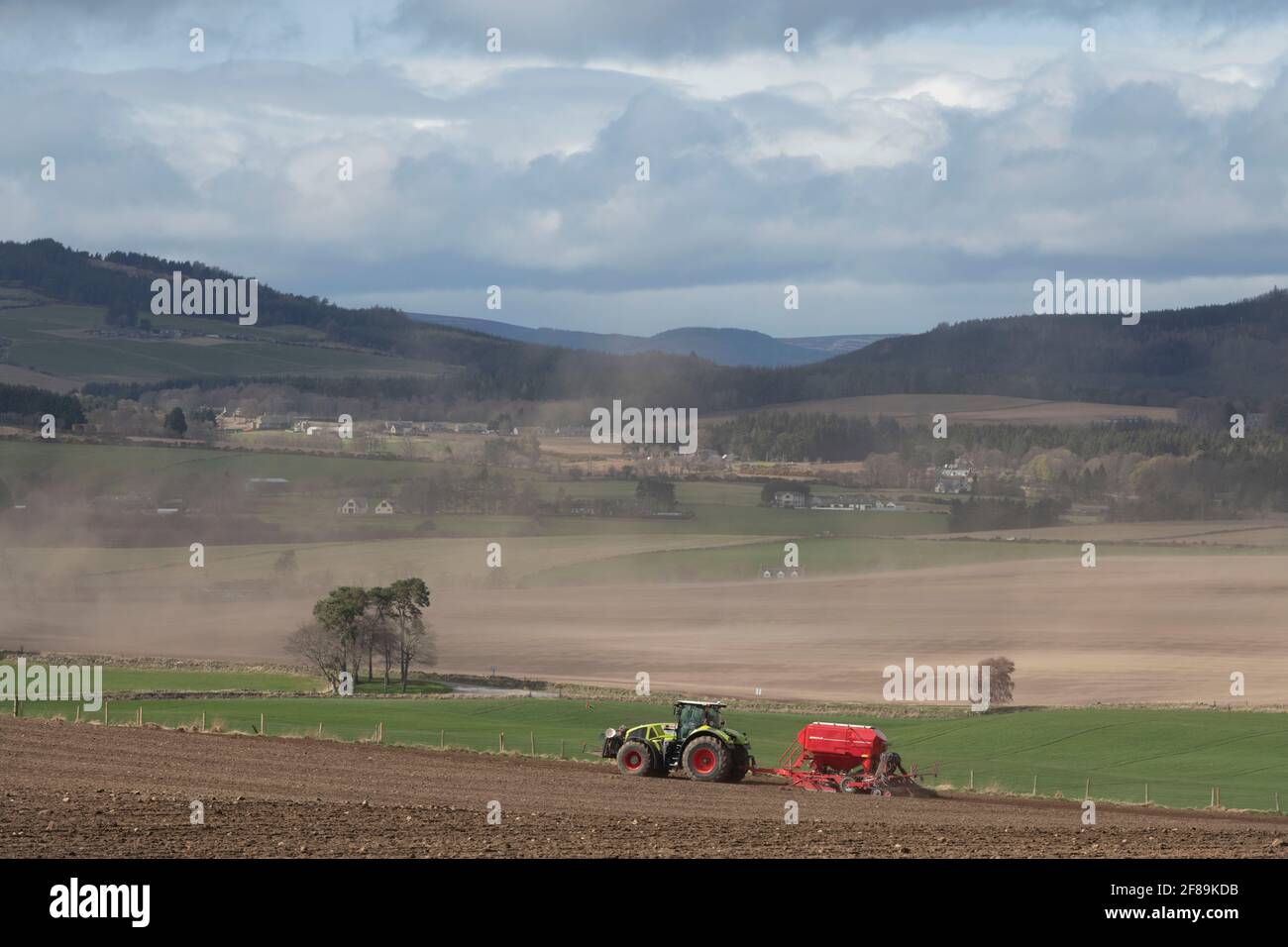 Vue sur la campagne du Barren Aberdeenshire en direction de la Suie Au printemps avec un fermier semis d'une récolte sur un Après-midi venteux Banque D'Images