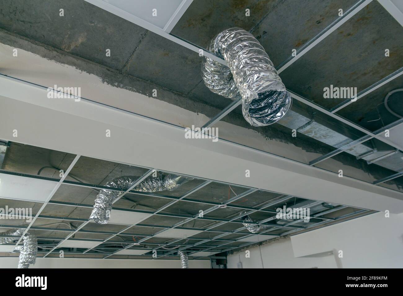 Le plafond suspendu dans le bureau en construction. Le faux système de plafond. Cadre de plafond suspendu et panneau en construction au sein du bâtiment Banque D'Images