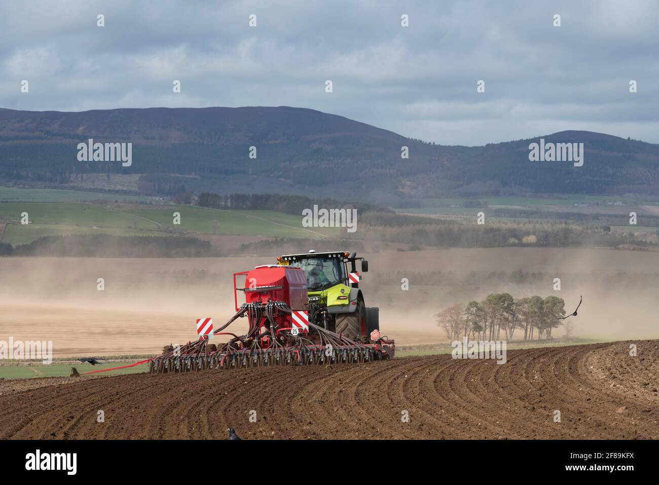 Un agriculteur plantant des semences en Écosse rurale comme vent souffle Sol d'un champ en arrière-plan Banque D'Images