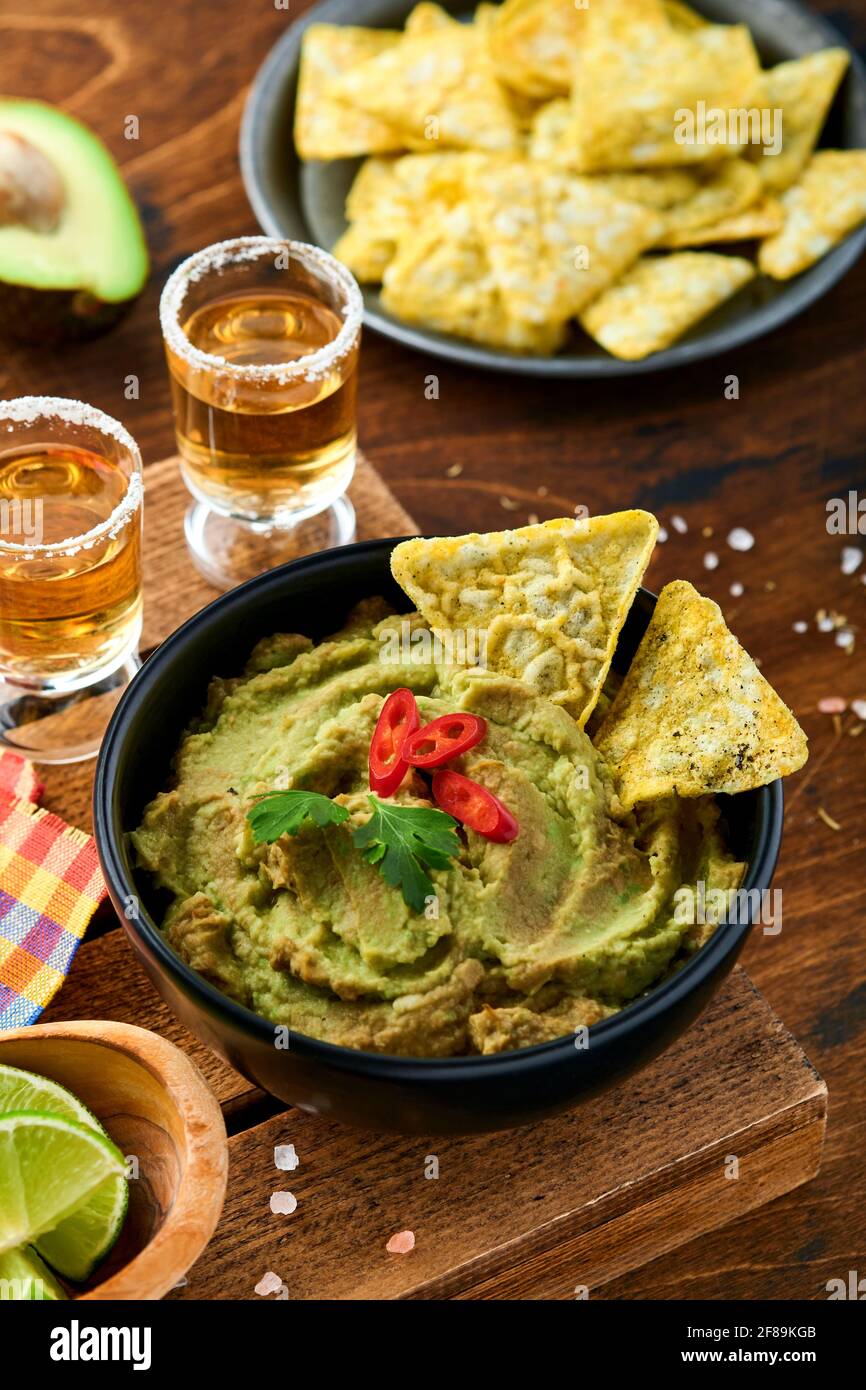 Guacamole. Sauce mexicaine traditionnelle latinaméricaine dans un bol noir  avec avocat et ingrédients et nachos de maïs. Propagation de l'avocat. Vue  de dessus. Copier sp Photo Stock - Alamy