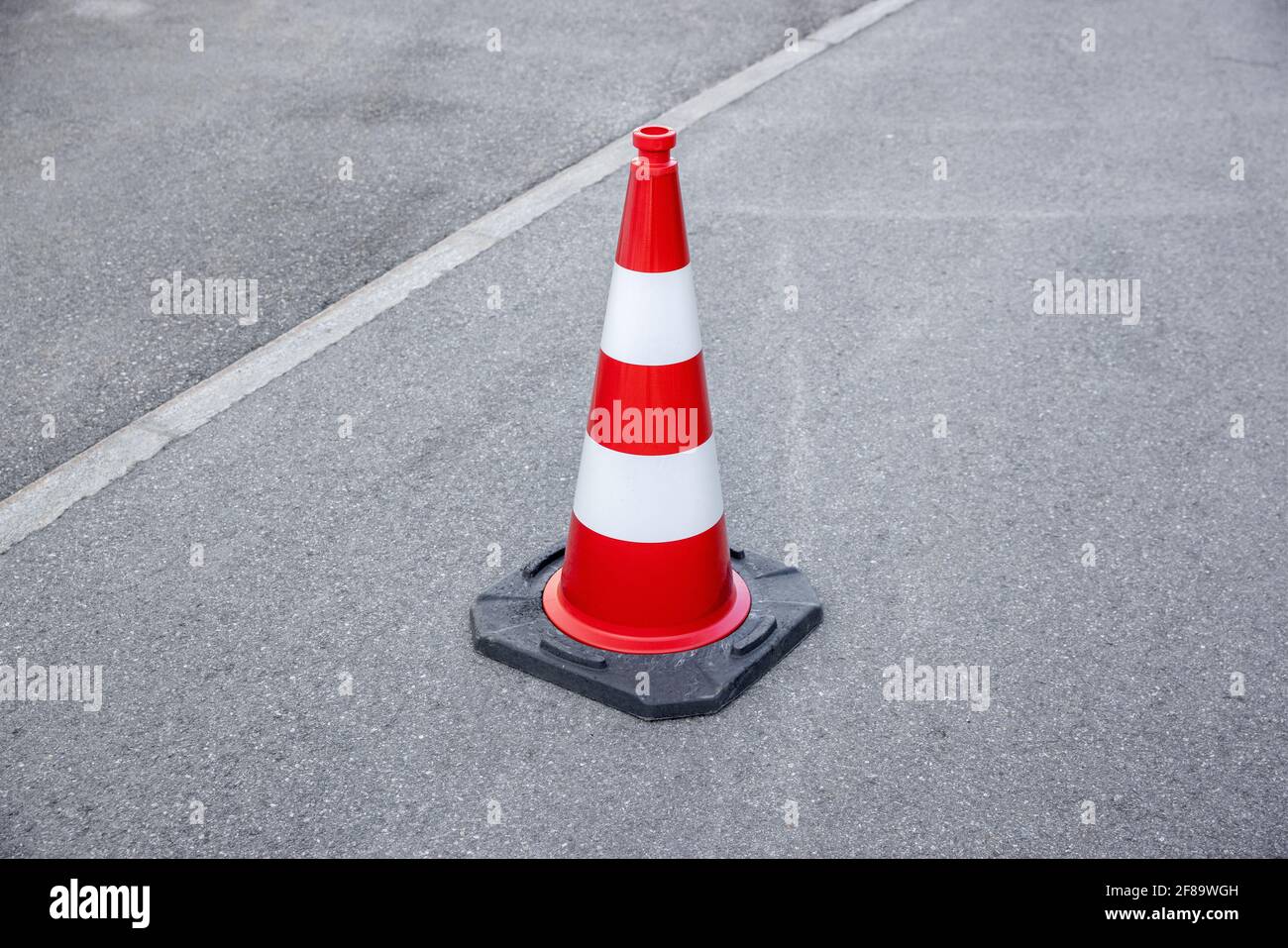 un seul cône d'avertissement rayé rouge et blanc sur l'asphalte gris, le jour sans personne Banque D'Images