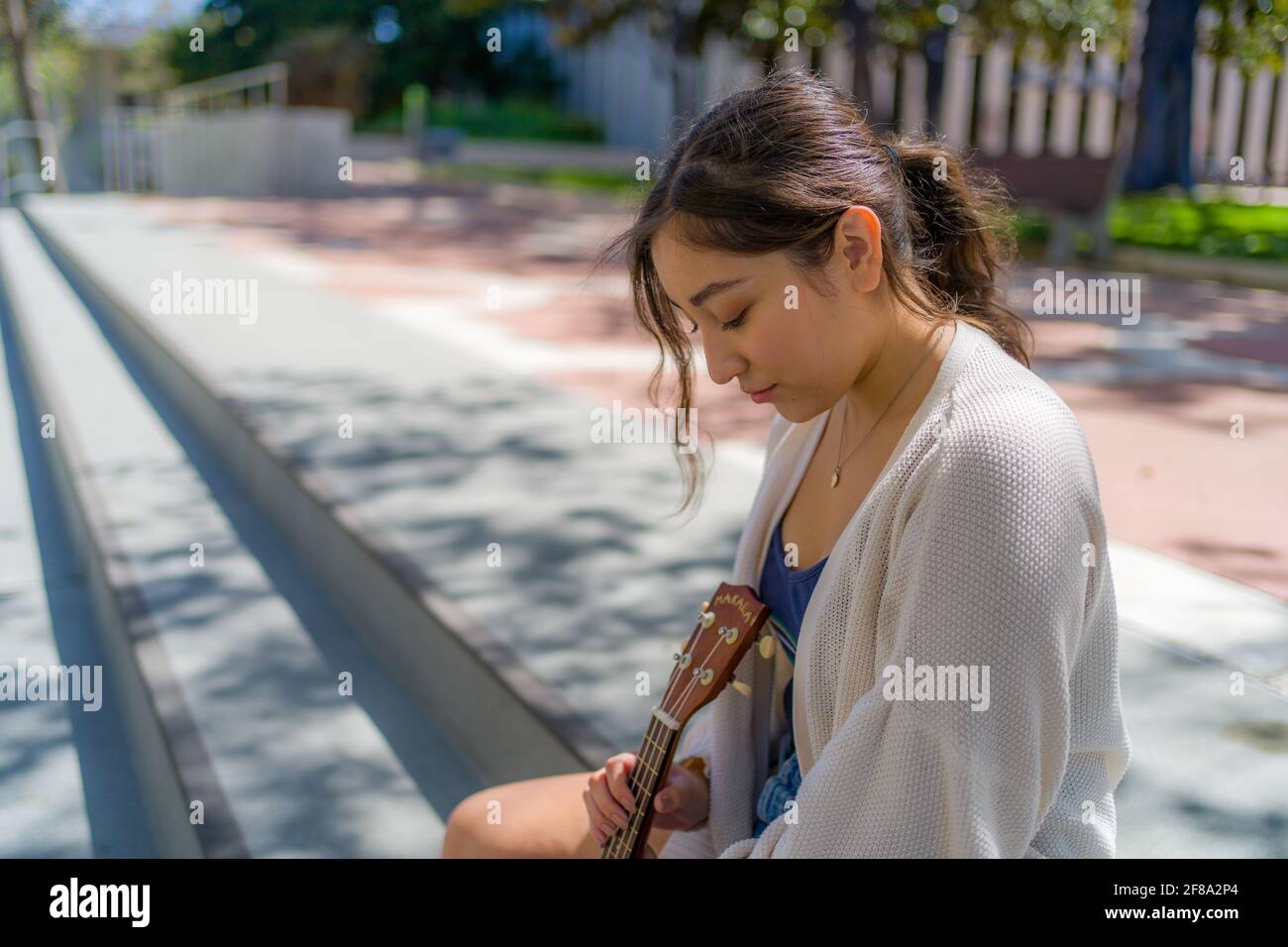 Petite adolescente asiatique assise avec ukulele Banque D'Images