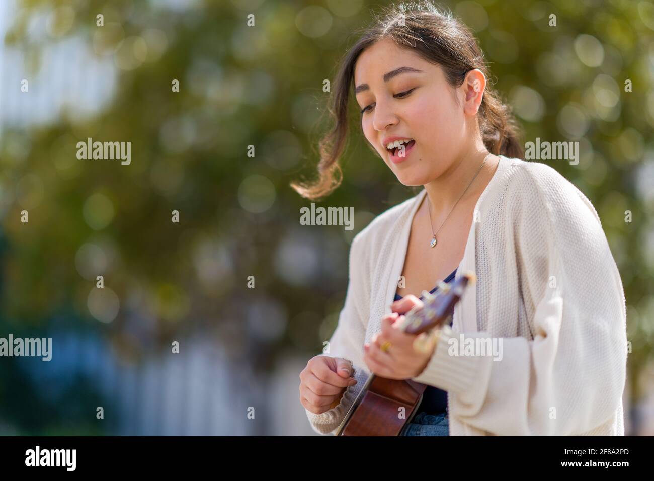 Petite adolescente asiatique jouant Ukulele et chantant Banque D'Images