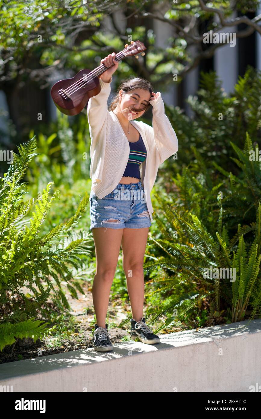 Petite adolescente asiatique debout avec ukulele Banque D'Images