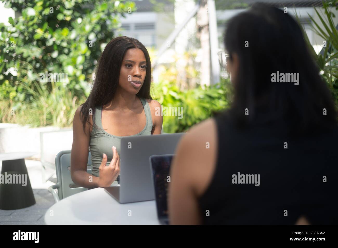 Portrait d'une jeune femme afro-américaine travaillant avec un ordinateur portable Ordinateur et parler à un collègue à l'extérieur Banque D'Images