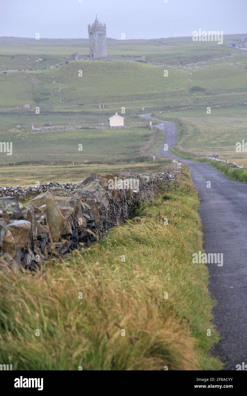 Mur de pierre et route menant à Mist et à Castle Ruins à distance, Irlande rurale Banque D'Images