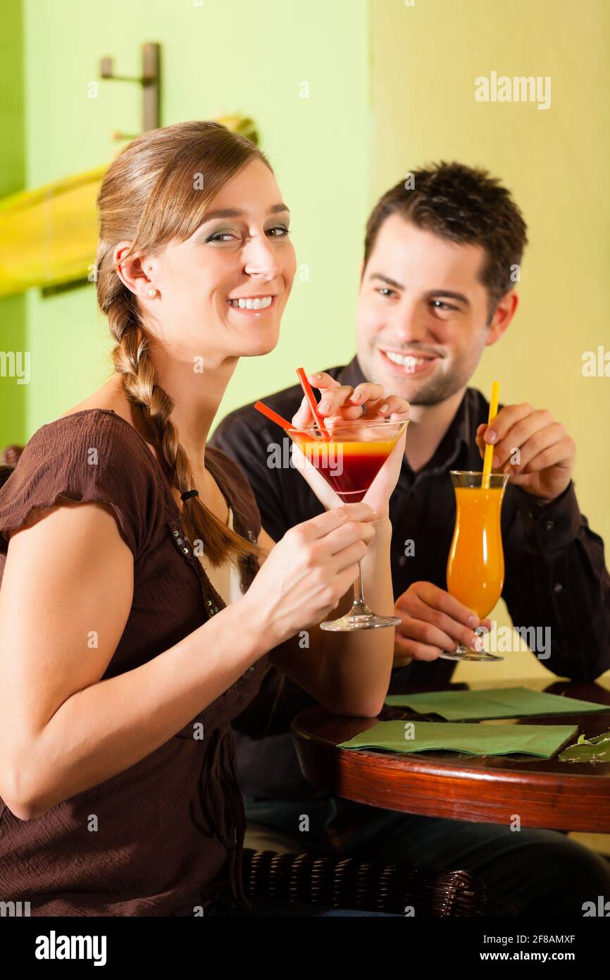 Un jeune couple heureux qui boit des cocktails au bar ou au restaurant ...