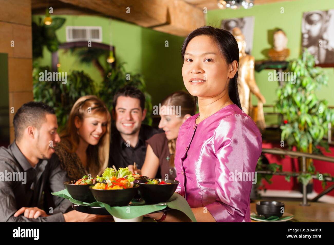 Les jeunes de manger dans un restaurant thaïlandais, la serveuse apporte les plats, le riz et d'autres Banque D'Images
