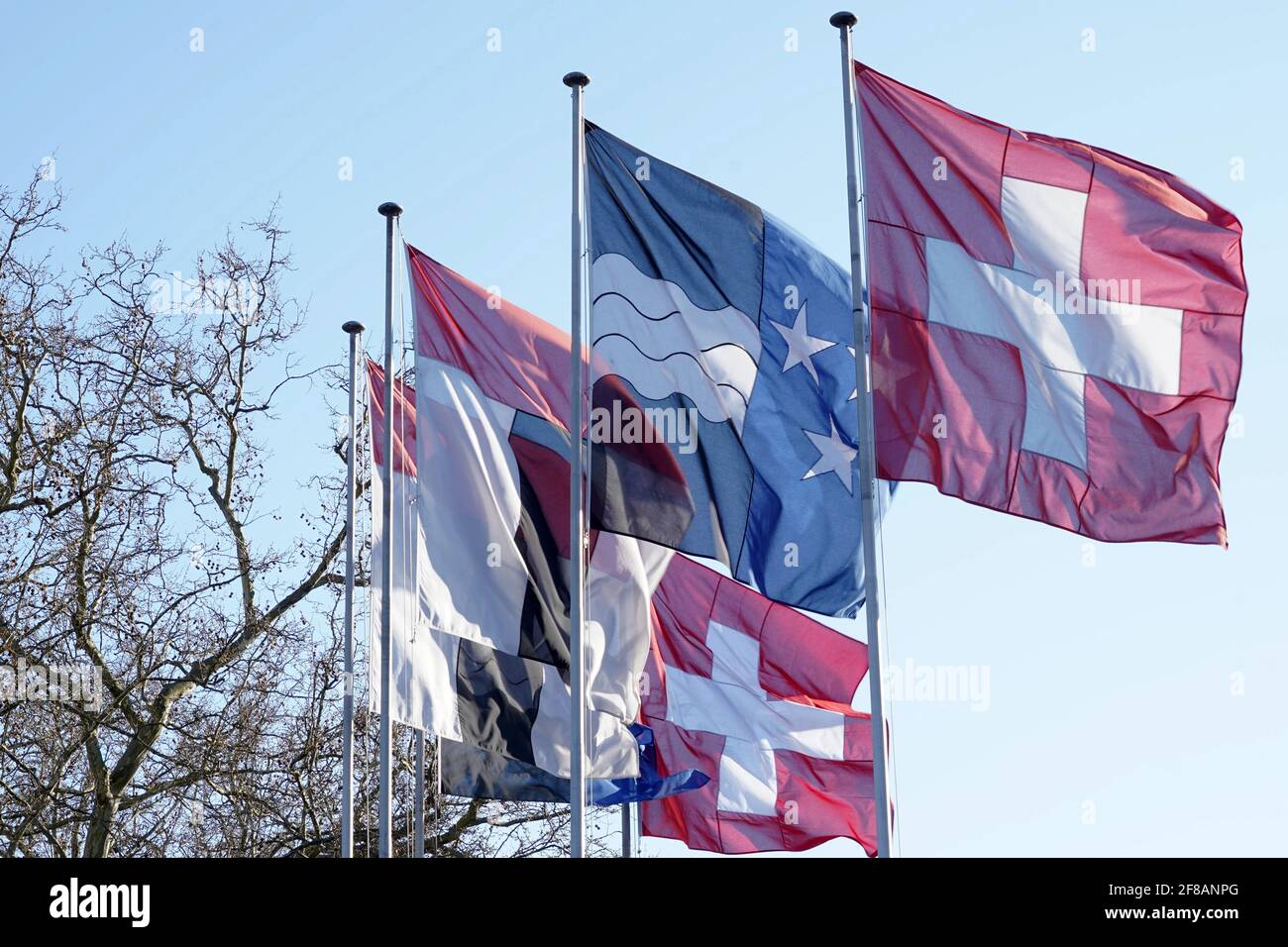 Drapeau fédéral suisse, drapeau cantonal du canton d'Argau et drapeau municipal de la ville de Baden. Ils agent dans le vent sur des poteaux métalliques sur l'arrière-plan. Banque D'Images