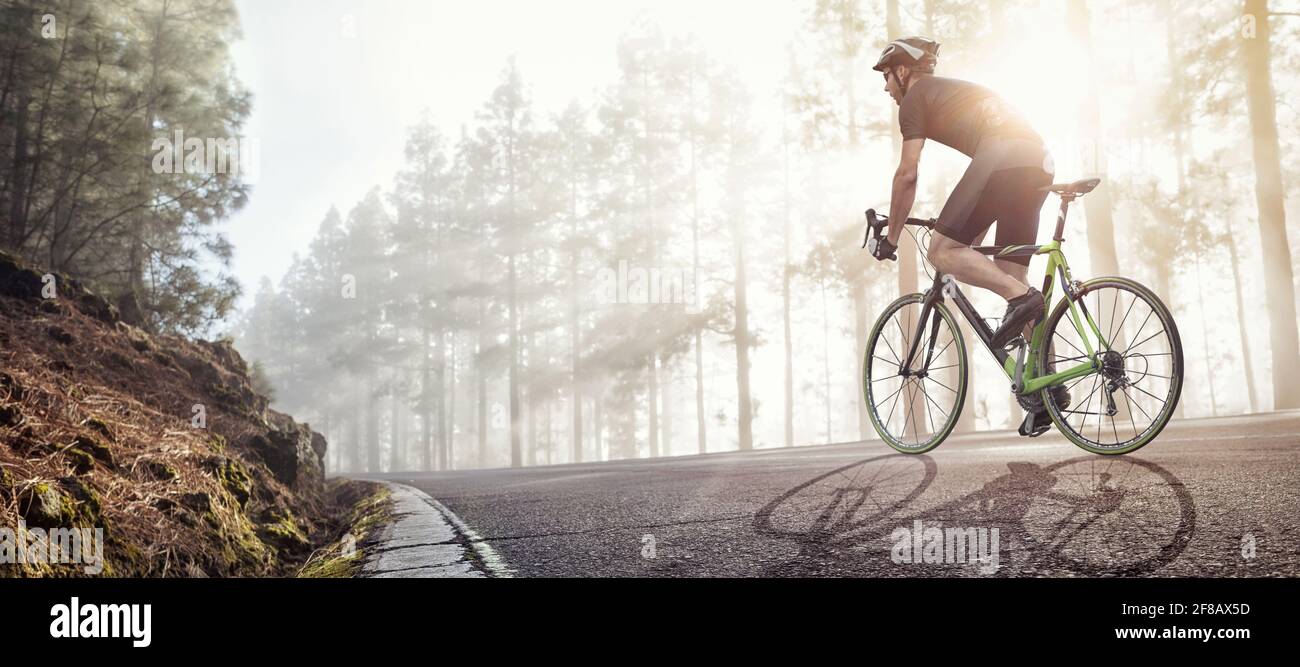 Cycliste avec un vélo de course sur une forêt brumeuse route Banque D'Images