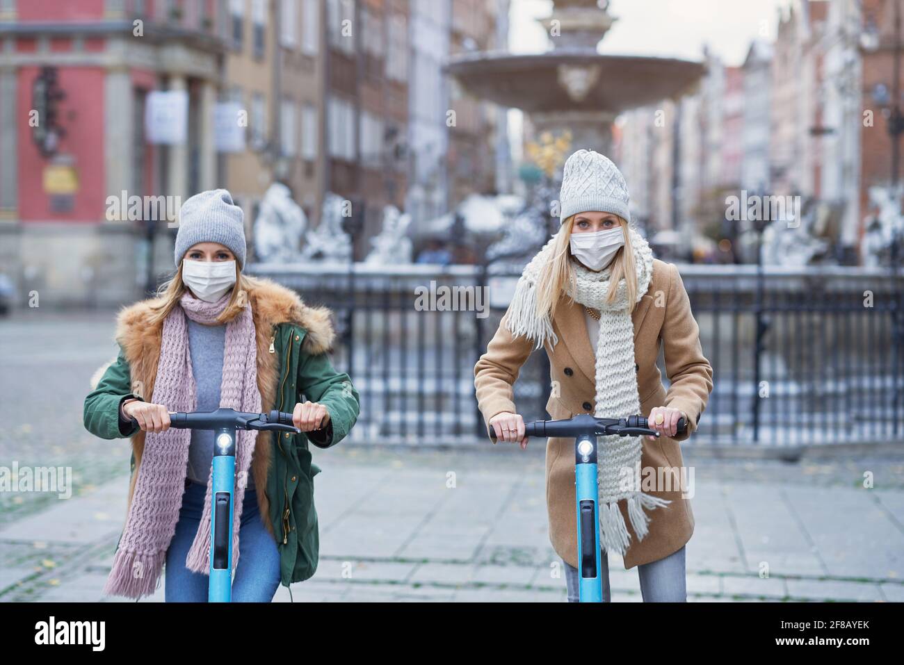 Filles amis portant des masques de visage et de transport sur le scooter dedans la ville Banque D'Images