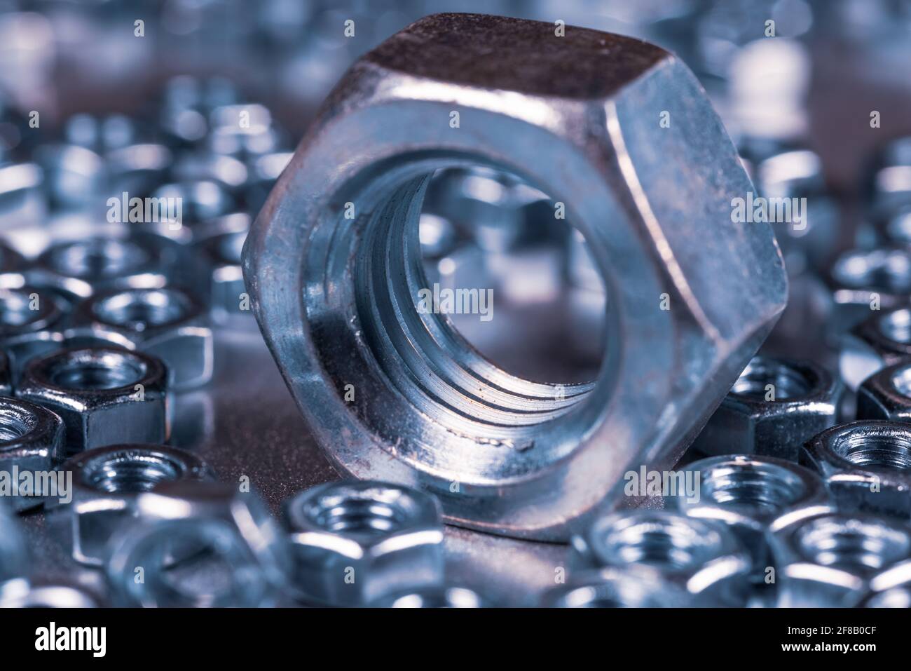 Un gros écrou repose sur un tas de petits écrous Banque D'Images