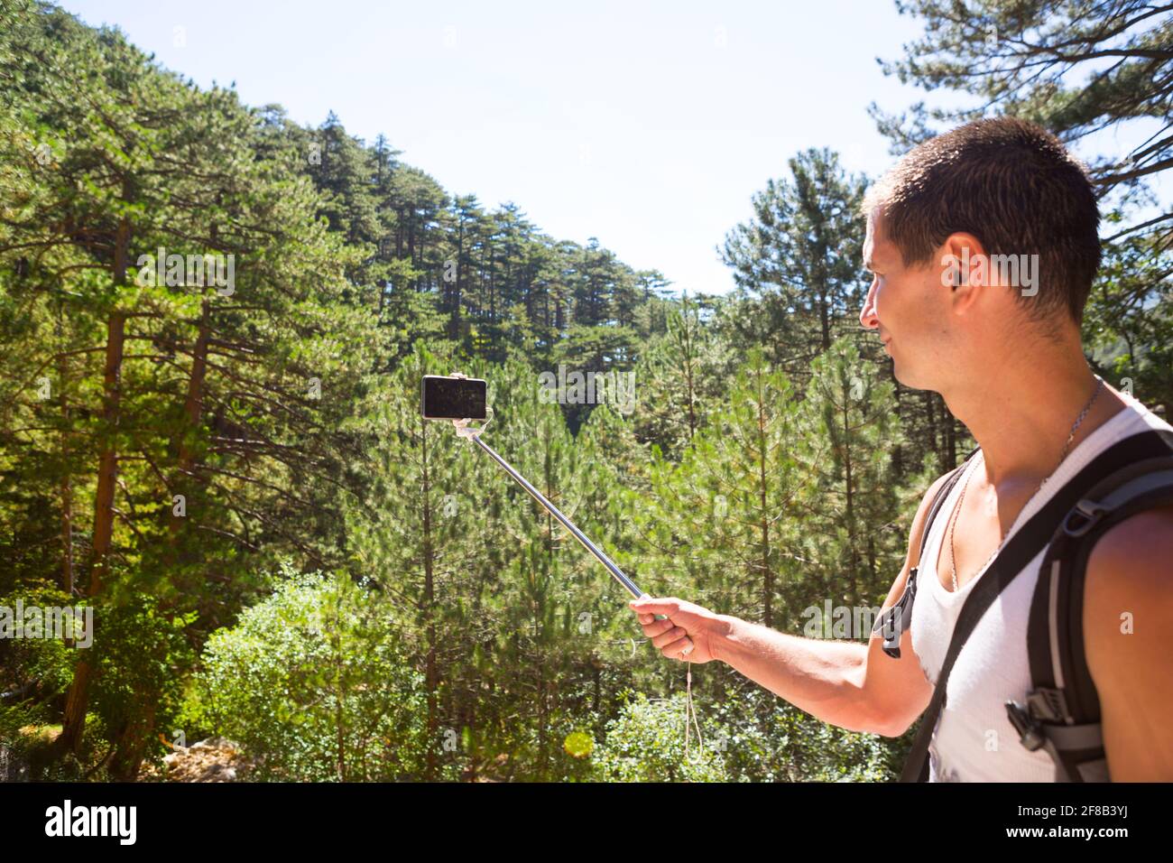 Un touriste mâle avec un sac à dos prend des photos sur un smartphone avec un bâton de selfie de belles vues sur la nature lors de trekking. Tourisme actif, randonnée, dôme Banque D'Images