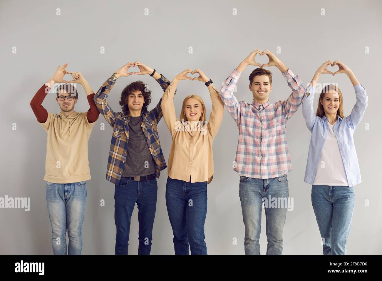 Groupe d'étudiants adolescents montrant de la sympathie d'amour faire le geste de coeur prise de vue en studio Banque D'Images
