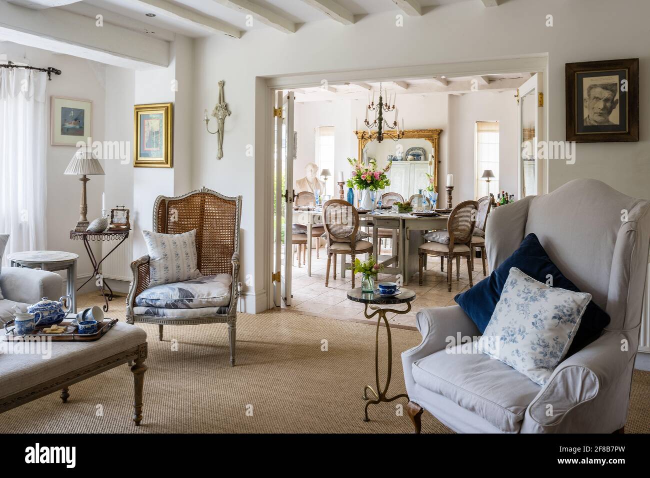 Fauteuils en rotin et Gustavian avec vue à travers les portes doubles dans les années 1930 West Sussex rénovation côtière. Banque D'Images