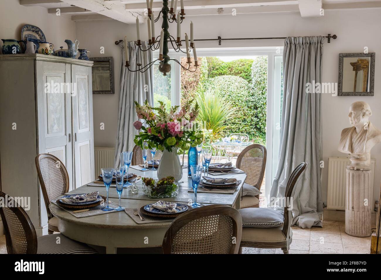 Verrerie sur table à manger avec vue sur le jardin dans les années 1930 West Sussex rénovation côtière. Banque D'Images