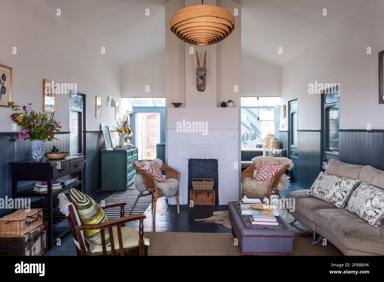 Coussins de la Guilde des designers, chaises en osier avec jetés en peau de mouton et lampe en bois spiralé de la Guilde des designers dans la maison de vacances rénovée de West Sussex. Banque D'Images